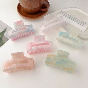 Macro detail of large acetate hair claws in assorted pastel marble colors and wave teeth