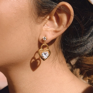 Dettaglio orecchini a cuore in zircone oro 18K indossati con ombre e luci creative