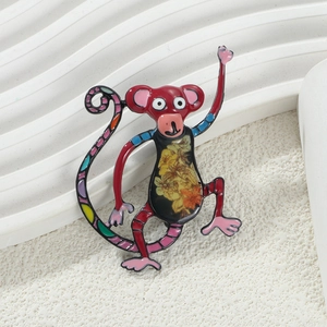 Detail of colorful enamel cartoon monkey brooch with golden flower patterns on white base