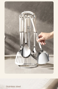 Polished stainless steel kitchen utensil set with white handles on a metal storage rack