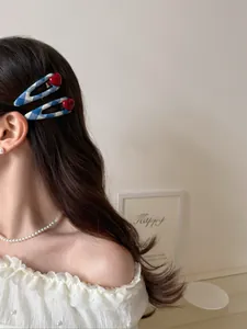 Close-up of blue and white checkered hair clips with red heart details on a female model