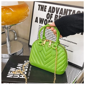 Detail of bright green jelly handbag with V-shaped ripples and golden chain strap
