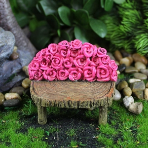 Miniature resin garden bench with pink roses and wood grain texture on green moss