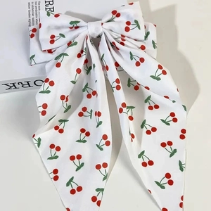 Detail of white bow hair clip with cherry print and long ribbons on a magazine