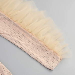 Detail of ruffled mesh dress with luxury rhinestone embellishments and beige fabric