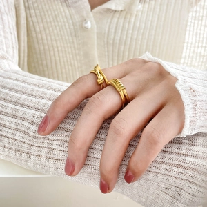 Detailed macro view of 18K gold-plated multi-layer knot and hollow cross rings for women