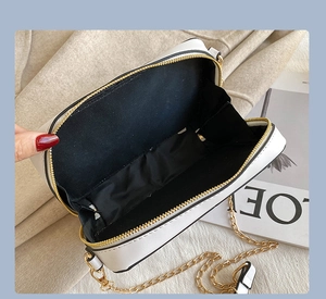 Detail view of radio-style crossbody bag with gold zippers and black fabric lining