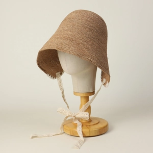 Detail of hand-woven straw bonnet hat featuring intricate lace trim and tie ribbons
