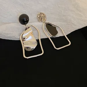 Asymmetric geometric earrings with wrinkled metal plates and glossy black spheres