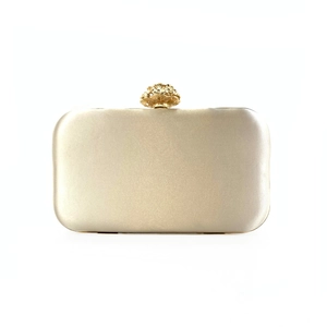 Detail of champagne gold evening clutch with satin finish and floral metal clasp