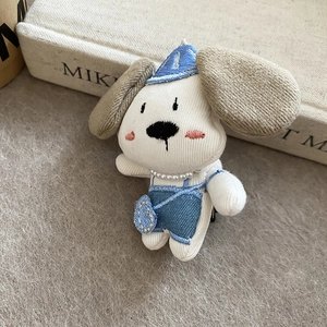 Detail of plush puppy hair clip with blue denim overalls and pearl necklace detail