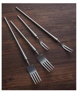 Macro view of matte silver stainless steel forks on dark wooden surface for dining