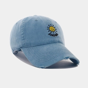 Detail of sunshine smile embroidery and distressed brim on light blue cotton baseball cap