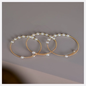 Ensemble de trois joncs dorés ornés de perles blanches et design tressé chic