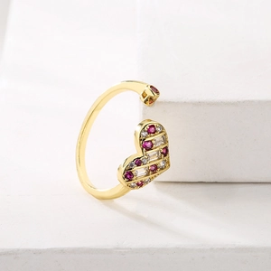 18K gold plated hollow heart open ring with red and white gemstones on white stone