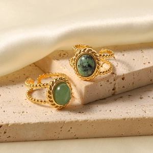 Vintage gold-plated titanium steel rings with natural green gemstones on a textured stone base