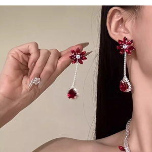 Detail of elegant floral drop earrings with red stones and zircon tassels on model