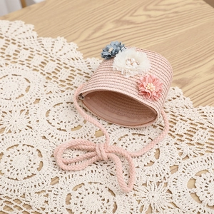 Dettaglio della borsa in paglia rosa per bambina con tre accenti floreali decorativi fatti a mano