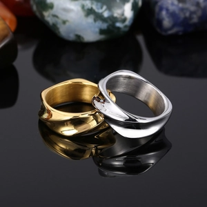 Macro shot of gold and silver irregular wavy rings on a reflective black surface