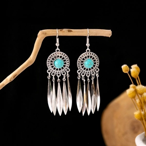 Close-up of bohemian silver earrings with turquoise stones on a rustic wood branch