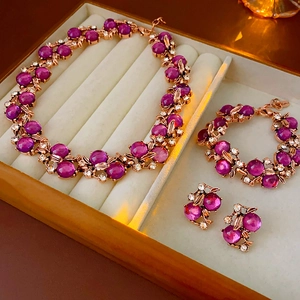 Vintage gold metal jewelry set with purple gemstones and rhinestones in beige box