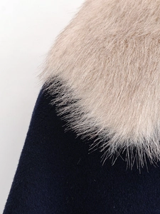 Close-up of fluffy faux fur collar on dark blue wool coat showing soft fabric texture