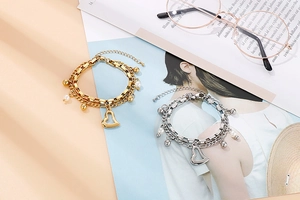 Vue détaillée de bracelets double couche en acier avec breloques cœur et perles sur un magazine