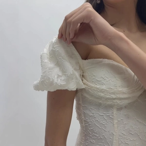 Robe blanche élégante en tissu jacquard avec manches bouffantes et dos ouvert