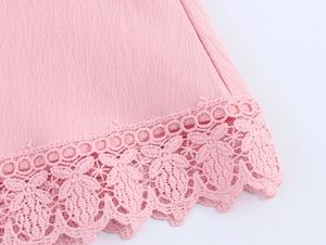 Close-up of pink dress hem featuring intricate floral lace trim and pleated fabric detail