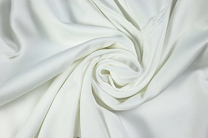 Macro shot of white knitted fabric texture with soft ripples and subtle glossy finish