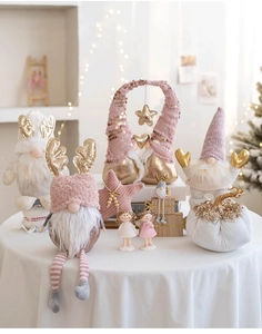 Pink and gold Christmas gnomes and angel dolls set on a warm festive background