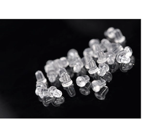 Macro shot of transparent silicone bullet-shaped earring backs on black reflective surface