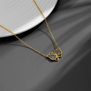 Elegant gold butterfly necklace featuring black zircon pavé wings on white ceramic plate
