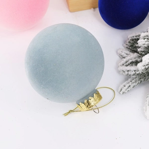 Close-up of light blue flocked Christmas ball with gold cap and string on pine branch