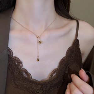 Détail du collier pendentif tournesol en œil de tigre porté sur une chaîne en Y dorée
