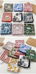 Close-up of cotton linen square scarves with printed patterns and crochet lace edges