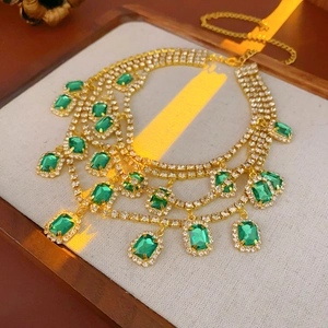 Close-up of emerald green square pendants on a layered gold rhinestone necklace