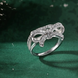 Detailed view of silver bow ring featuring sparkling zircons on dark green velvet background