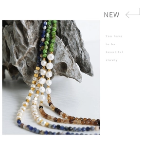 Detail of bohemian necklaces with natural stones and pearls on a grey stone background