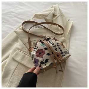 Detailed top view of floral knit bucket bag with brown leather drawstring and metal feet