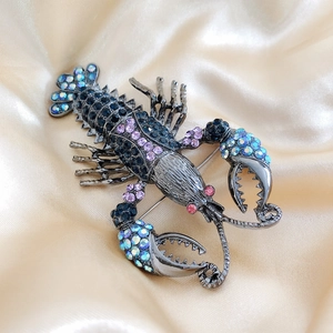 Macro shot of lobster brooch with blue and purple rhinestones on champagne satin silk