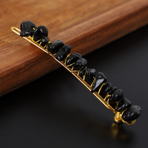 Macro detail of natural black crystal stones hand-wrapped with gold wire on a hair clip