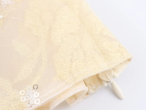 Detail of champagne lace fabric with sequins and an invisible teardrop zipper