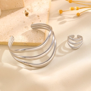 Détail d'un ensemble de bijoux avec bracelet et bague ondulés multicouches en acier argenté