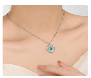 Detailed close-up of a silver sunburst necklace with a green gemstone on a model's neck