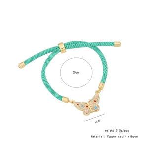 Dettaglio macro del bracciale a nastro verde con farfalla dorata e misure del prodotto