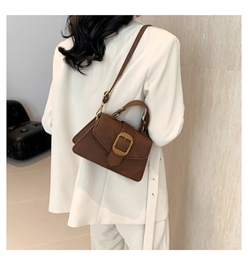 Brown faux leather crossbody bag with gold buckle worn on a white blazer outfit