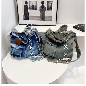 Detail of frayed edge denim shoulder bags in dark blue and grey with lace-up design