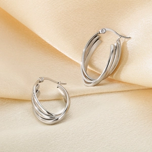 Detailed view of silver triple-layered irregular hoop earrings on champagne silk fabric