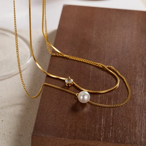 Detail of layered gold titanium necklace set with a zircon solitaire and white pearl pendant